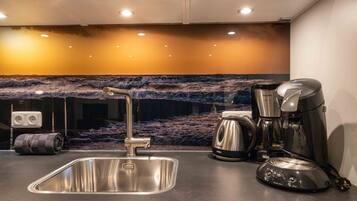 A modern kitchen with a stainless steel sink, a coffee maker, and a kettle.