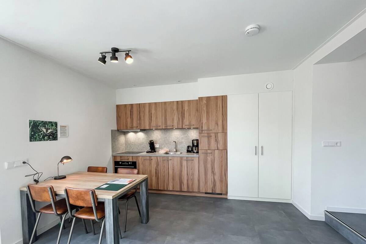 A modern kitchen with wooden cabinets, a dining area with a table and chairs, and a small kitchenette.