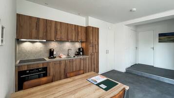 A modern kitchen with wooden cabinets, a stainless steel sink, and a dining area with a wooden table and chairs.