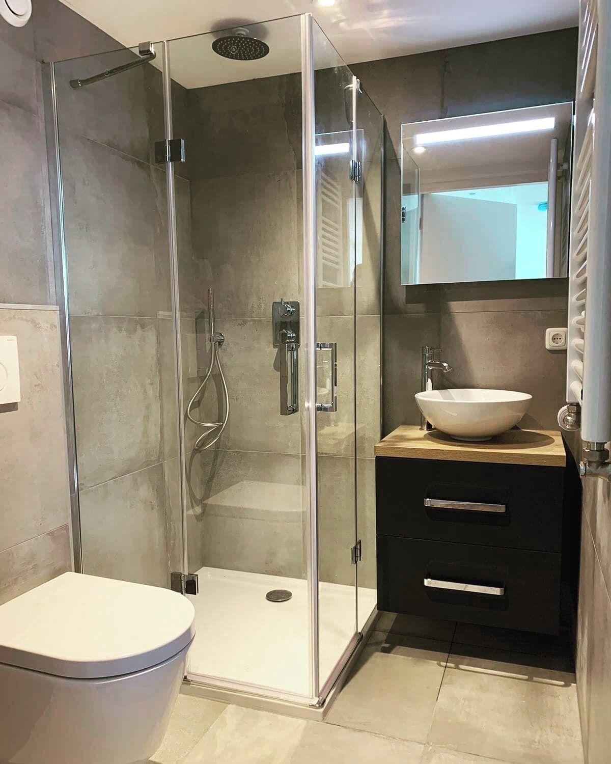 A modern bathroom with a glass-enclosed shower, a white sink, and a black cabinet.