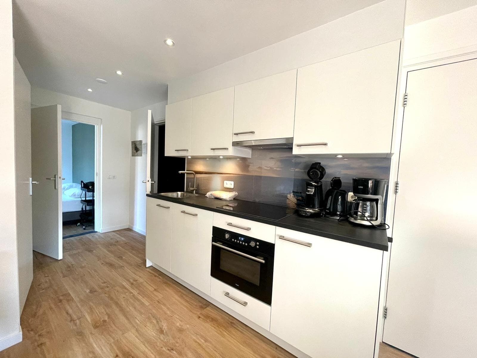A modern kitchen with white cabinets, a black countertop, and a built-in oven.