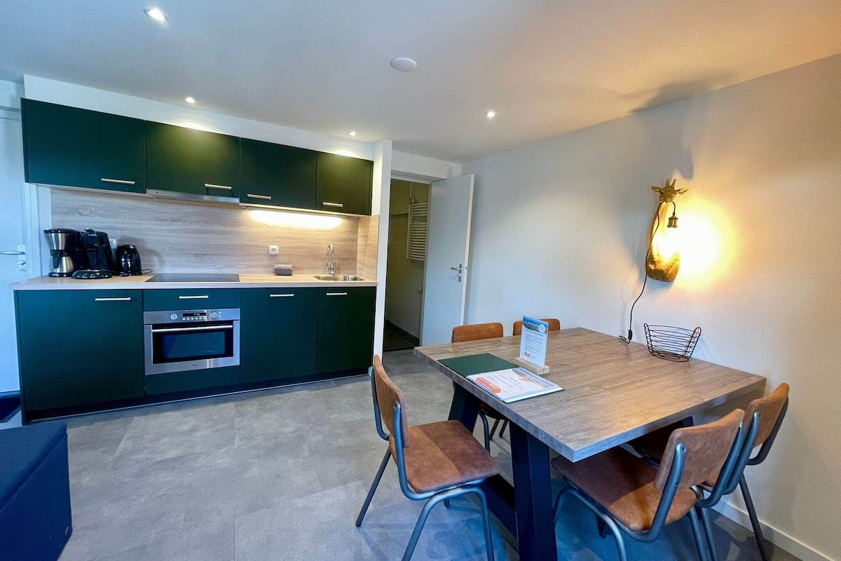 A compact kitchen with modern appliances and a dining area with a wooden table and four chairs.