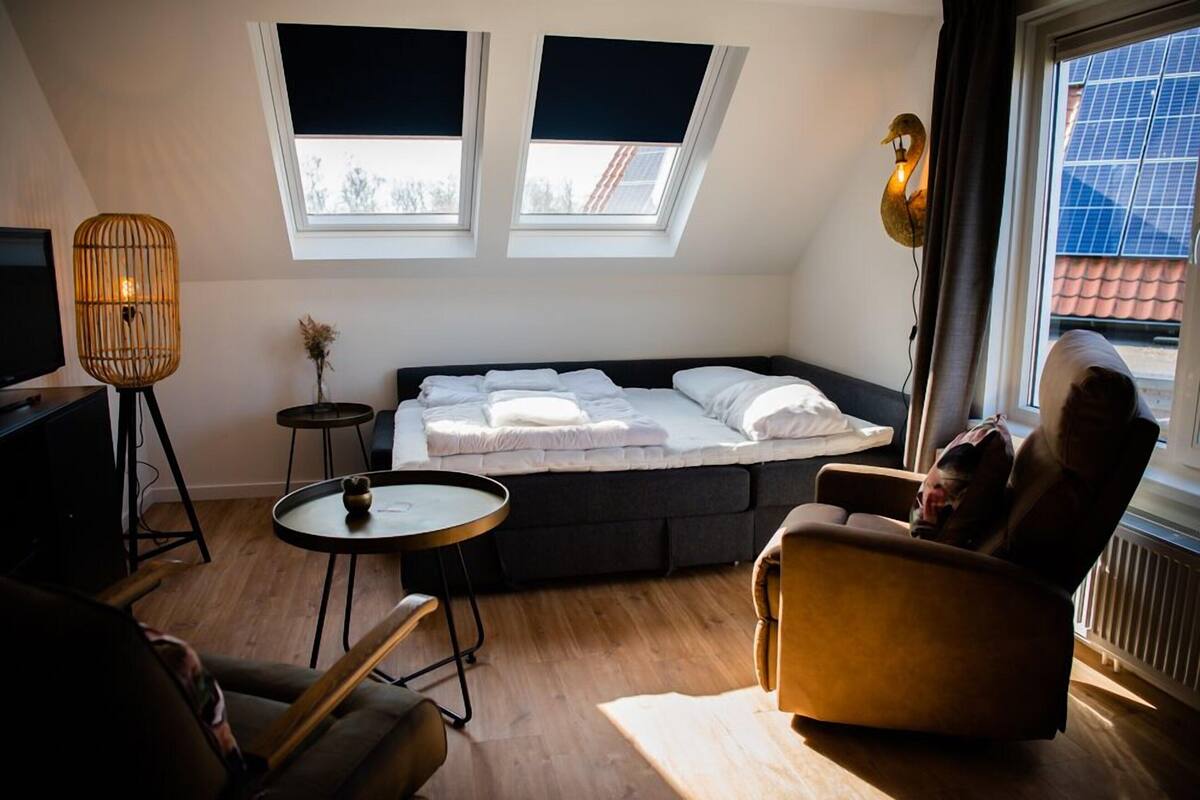 A modern room with a bed, a chair, a small table, and a lamp.