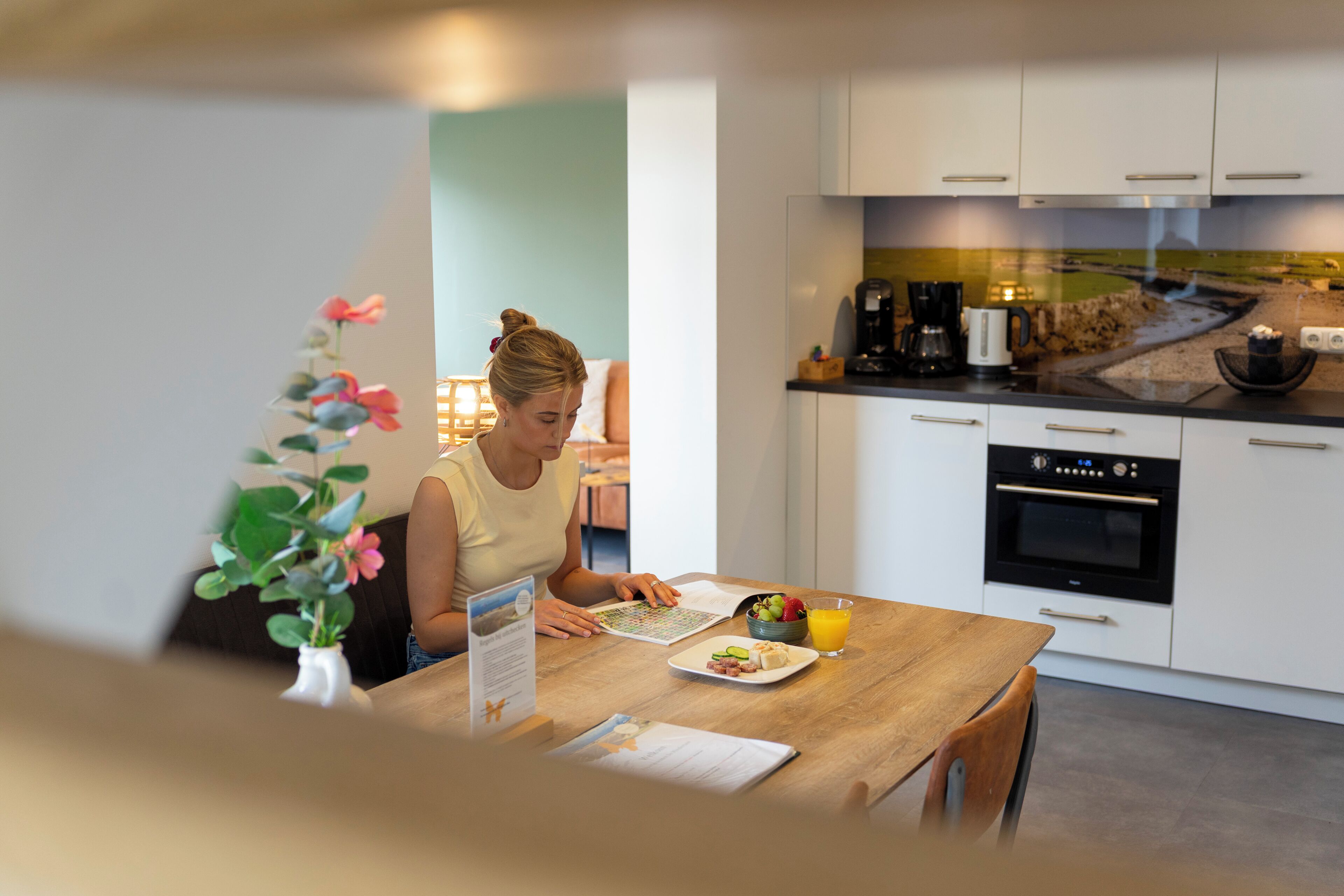 Una cucina moderna con mobili bianchi, una macchina da caffè e un tavolo da pranzo con un vaso di fiori.