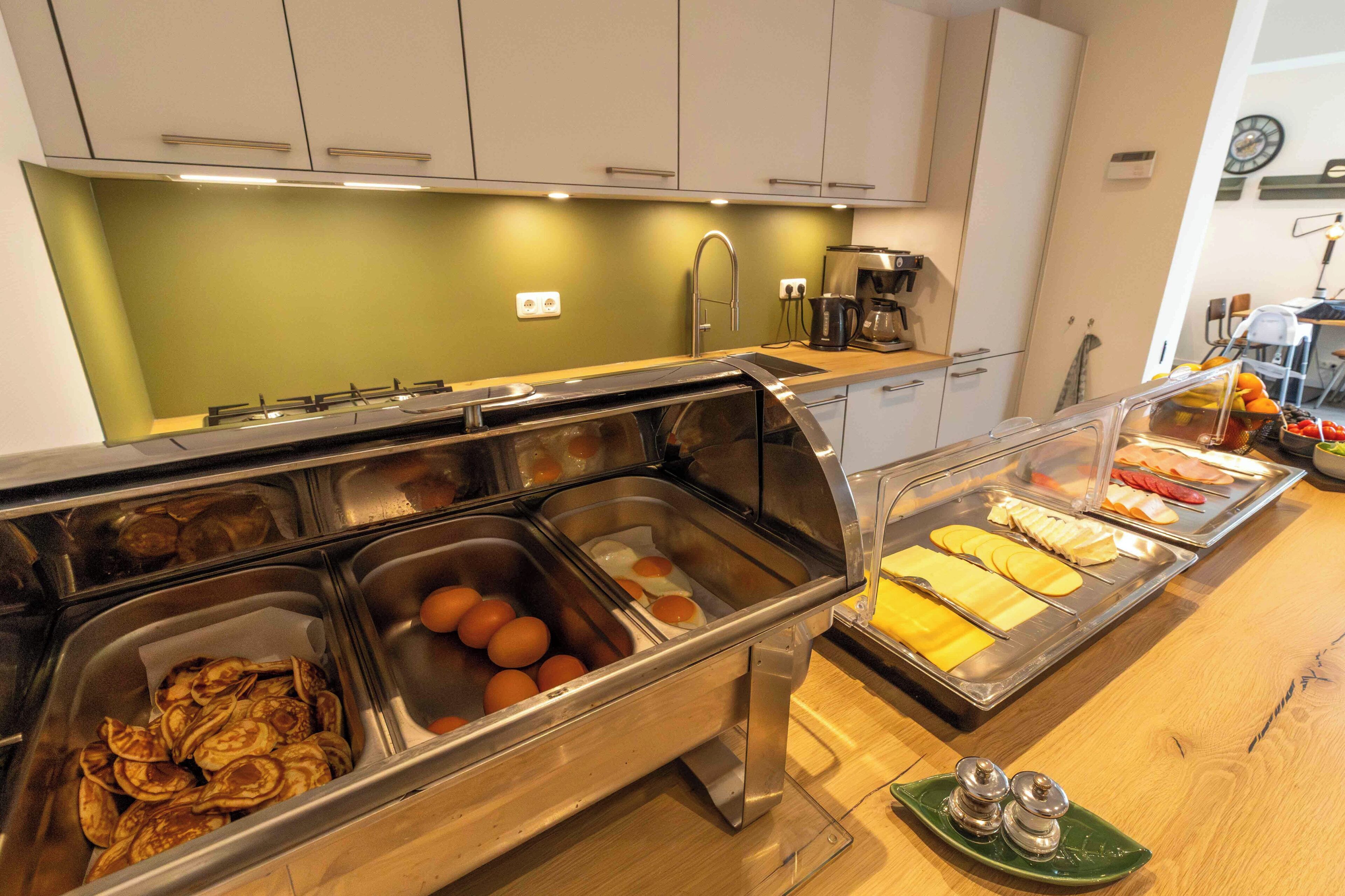 Un bufé con diferentes opciones de comida, una máquina de café y un lavamanos.