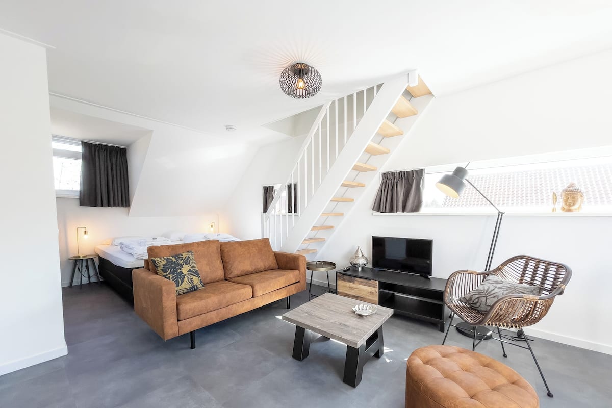 A modern living room with a sofa, coffee table, TV, and a staircase.