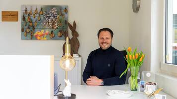 Ein Mann sitzt an einem Tisch mit einer Tulpenvase, einer Wanduhr und einer Schmetterlingsdekoration.