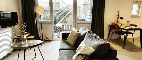 A modern living room with a sofa, a dining table, and a TV.