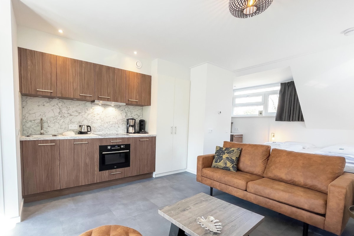 A compact living space with a kitchenette, a sofa, a coffee table, and a window.
