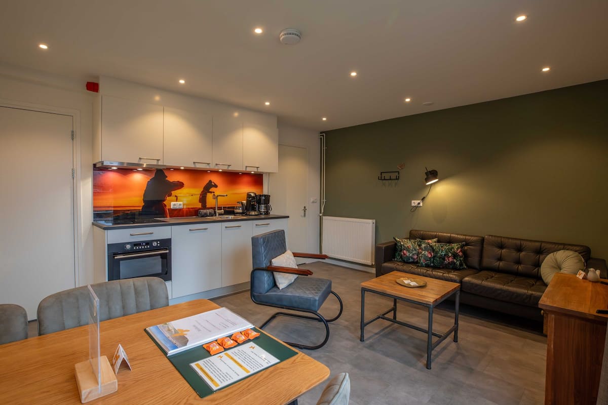 A modern living room with a sofa, coffee table, and a dining area with a table and chairs.