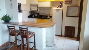 Une cuisine compacte avec un îlot central, des meubles blancs et un four à micro-ondes.