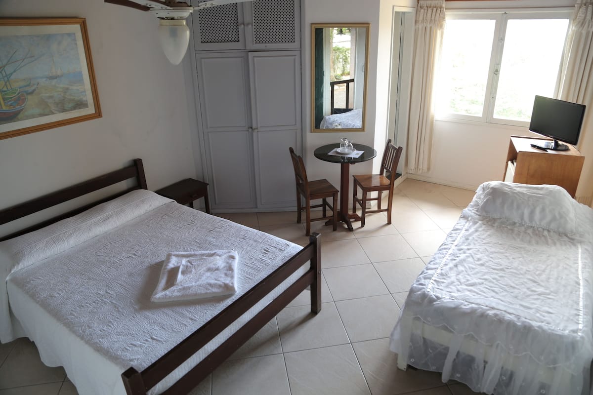 A hotel room with a bed, a desk with a chair, a television, and a window with curtains.