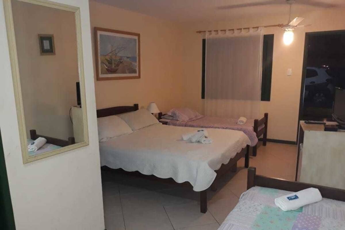 A hotel room with two beds, a ceiling fan, a window with curtains, and a view of a car outside.