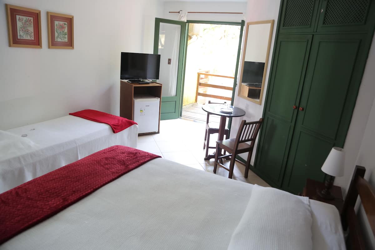 A hotel room with two single beds, a TV, a small table, a chair, and a wardrobe.