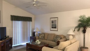 Ein Wohnzimmer mit Sofa, Couchtisch, Fernseher und Deckenventilator.