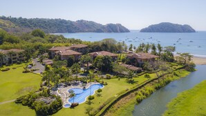 Un resort con varias construcciones, una piscina y vistas al mar.