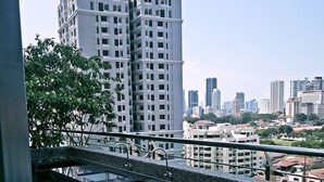 A modern building with a balcony, a cityscape in the background, and a logo with a crescent moon and stars. - 10Pax Designer Suite - Georgetown Penang (George Town)