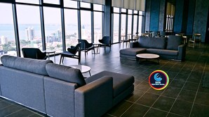 A modern lounge with grey sofas and chairs, a coffee table, and a view of the cityscape through large windows. - 10Pax Designer Suite - Georgetown Penang (George Town)