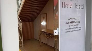 A hotel entrance with a modern design, including a wooden sloped ceiling and a glass door.