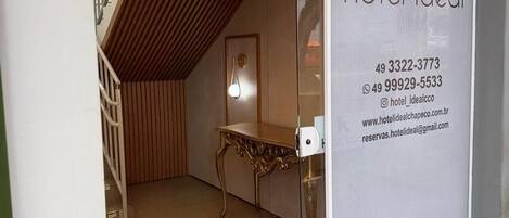 Entrada de hotel con diseño moderno, que incluye un techo inclinado de madera y una puerta de cristal.