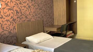 Quarto de hotel com duas camas, uma escrivaninha e um guarda-roupa.