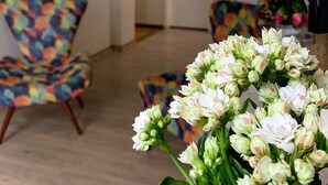 Een kamer met een kleurrijke stoel, een brandblusser aan de muur en een deur naar een andere kamer.
