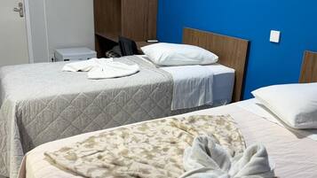 A hotel room with two beds, a wardrobe, and an air conditioning unit.