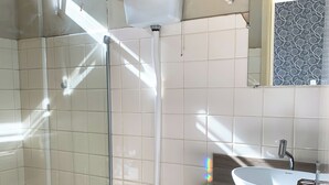 A bathroom with a toilet, a sink, a shower, and a trash bin. - Hotel Ideal (Chapecó)