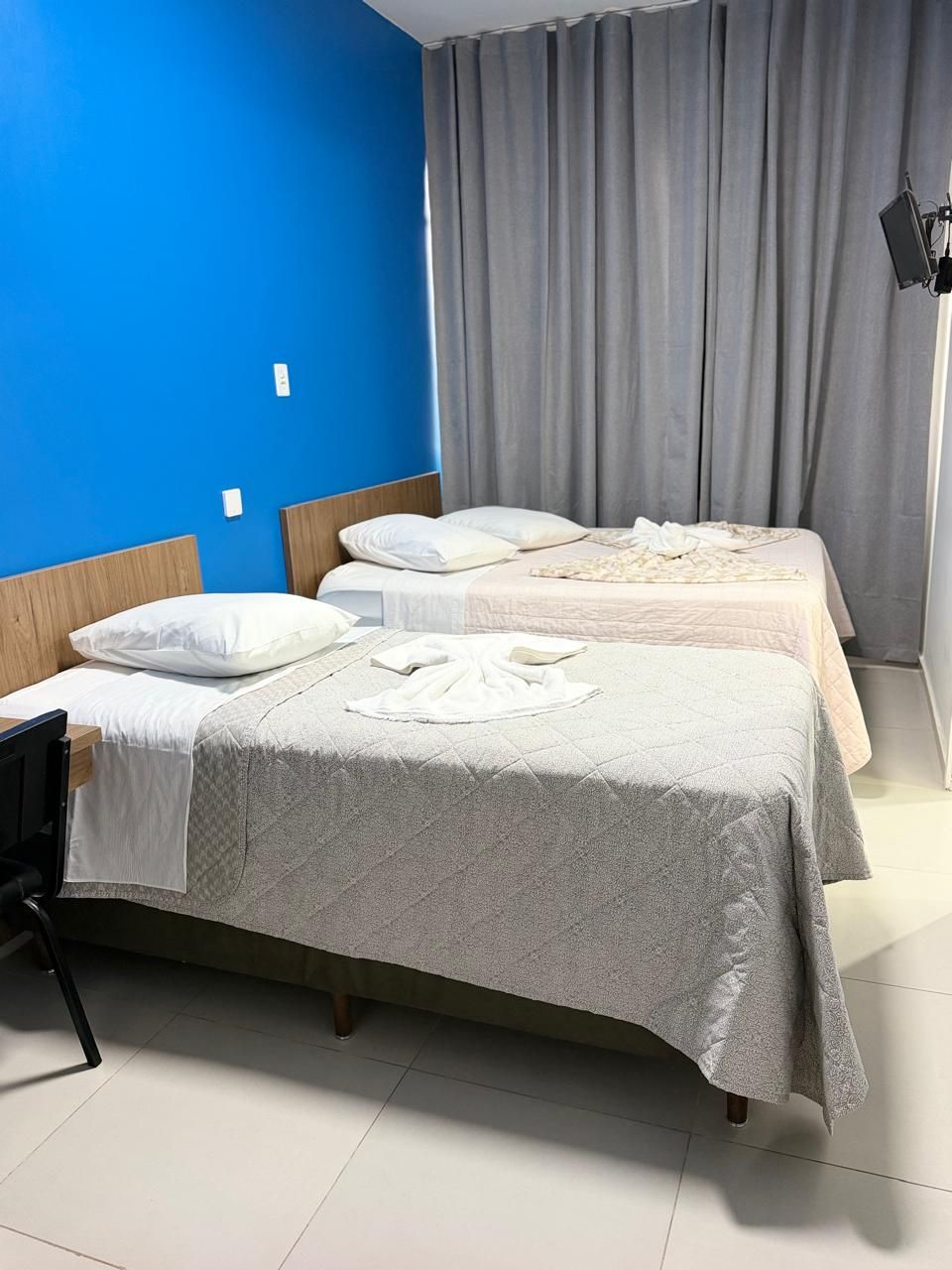 A hotel room with two beds, a desk, and a chair.