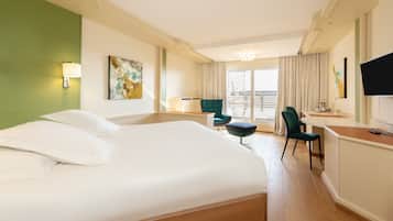 A hotel room with a large bed, a desk, a chair, and a television.