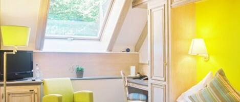 A room with a bed, a desk, a chair, a TV, and a window.