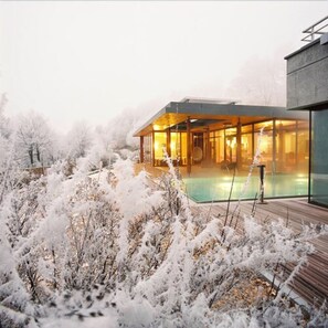A modern building with a glass facade, a wooden deck, and a pool area. - La Clairiere Bio & Spahotel (La Petite-Pierre)