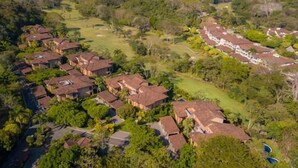 Vue aérienne d’un quartier résidentiel avec de nombreuses maisons, un terrain de golf et un grand bâtiment doté d’un toit rouge.