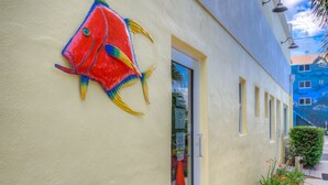 A building with a colorful fish mural on the wall, a door, and a window.