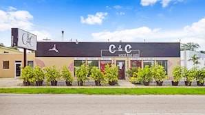 A building with a sign reading "C&C wood fired eats" and a menu board listing items like wood, fired, eats, drinks, salumi, and fromage.