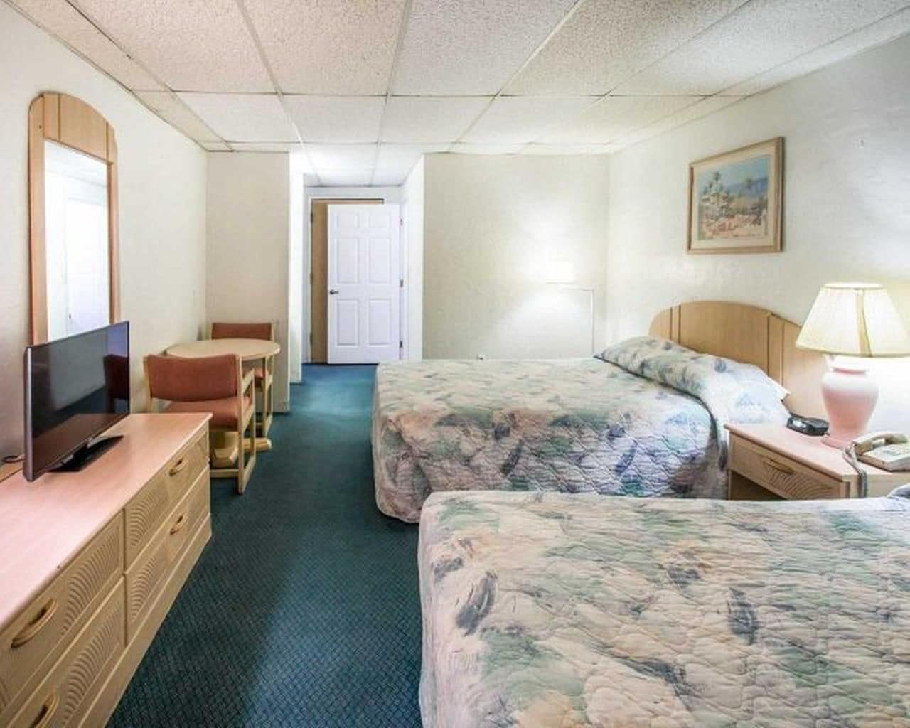 A hotel room with two beds, a TV, a desk, and a chair.