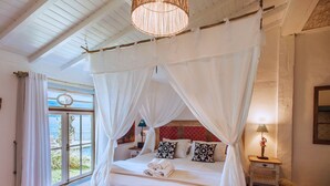 Ein Schlafzimmer mit Himmelbett, einer Bank, einem Nachttisch und einer Lampe.