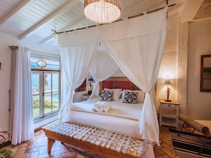 Ein Schlafzimmer mit Himmelbett, einer Bank, einem Nachttisch und einer Lampe.
