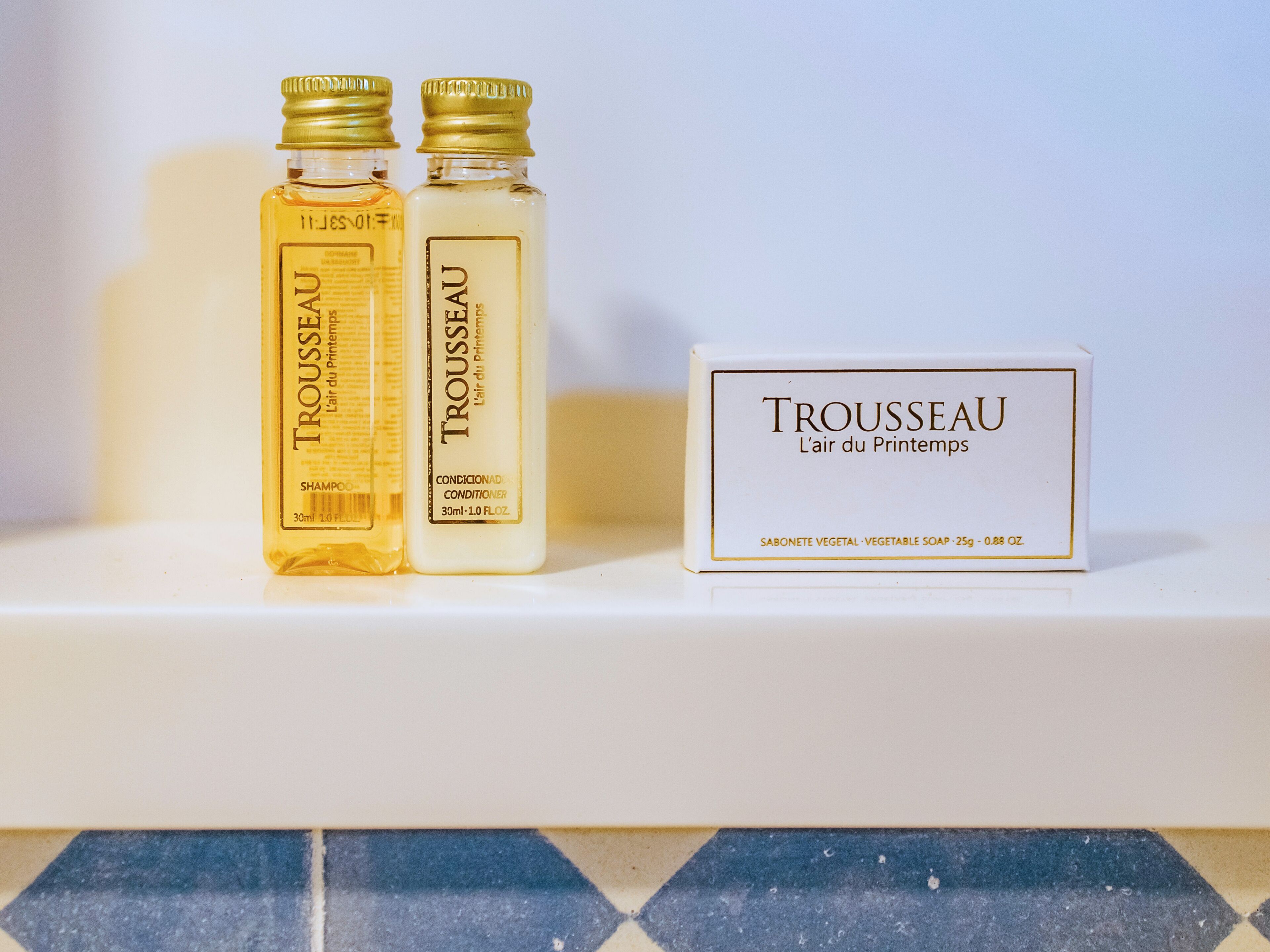Two bottles of Trousseau conditioner and a box on a shelf.