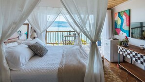 Ein Schlafzimmer mit Bett, Schreibtisch, Stuhl, Tisch und Meerblick.