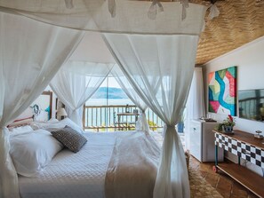 Ein Schlafzimmer mit Bett, Schreibtisch, Stuhl, Tisch und Meerblick.