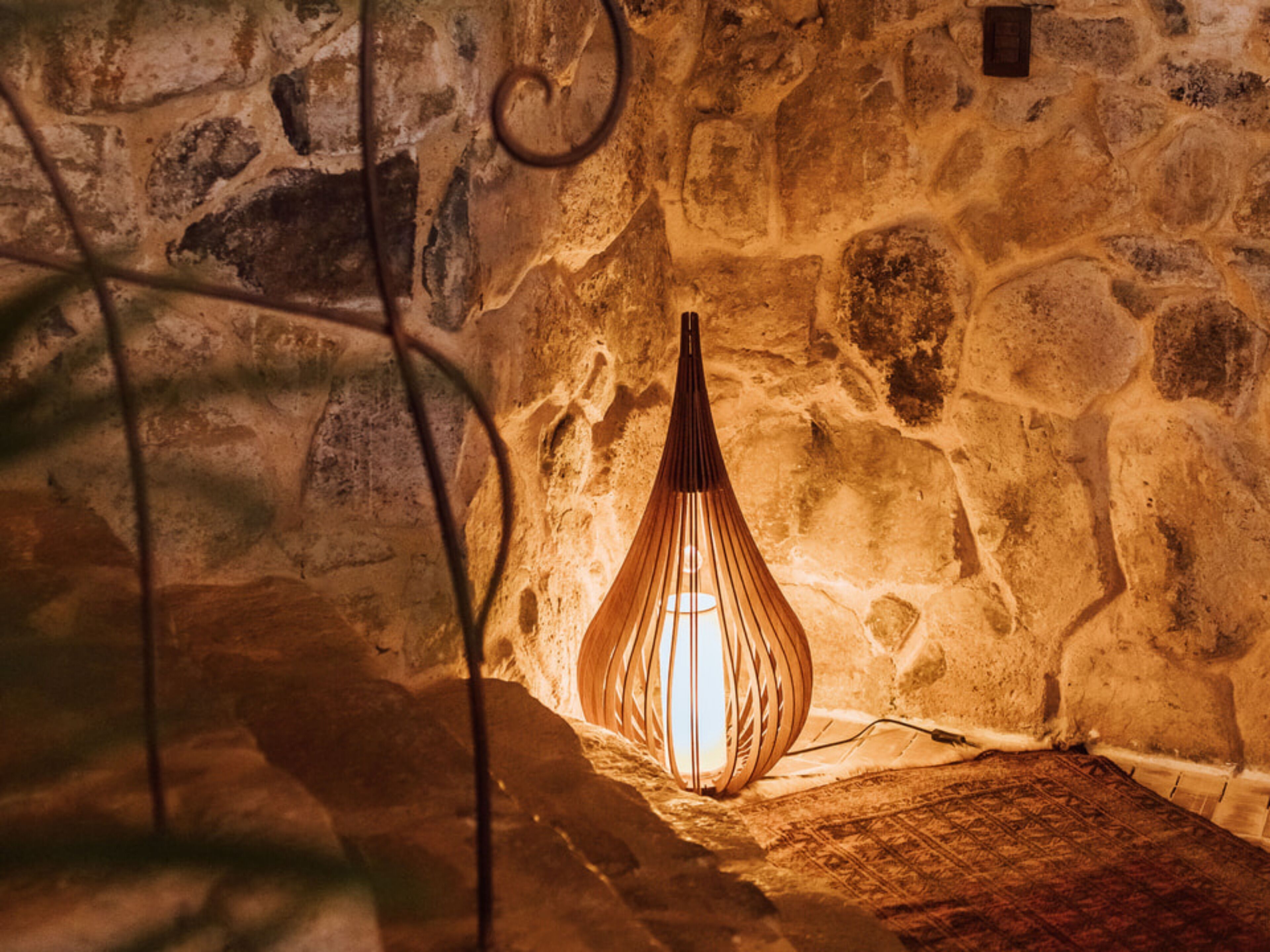 A stone wall with a wooden, ribbed light fixture.