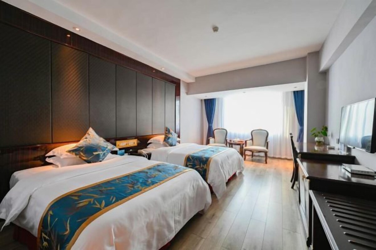 Habitación de hotel con dos camas, un piano, un escritorio y vistas al exterior.