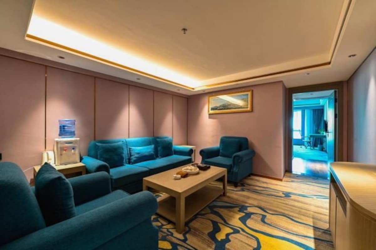A modern hotel room with a sofa set, a coffee table, and a painting on the wall.