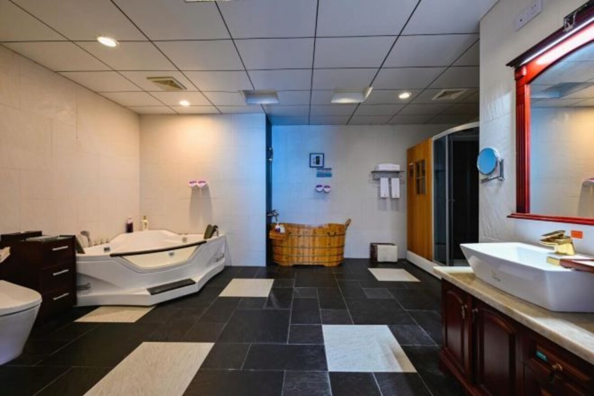 A modern bathroom with a bathtub, a large mirror, and a vanity with a sink.