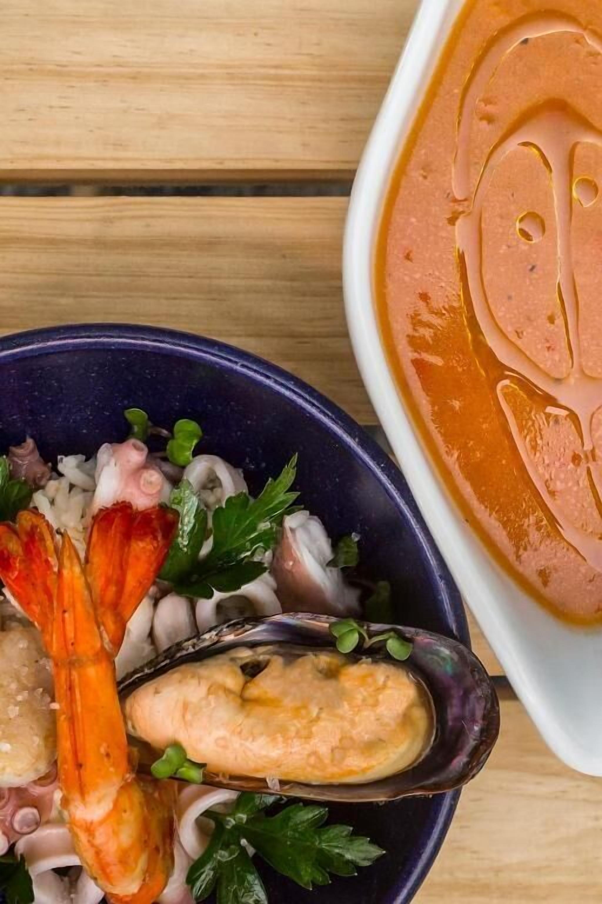 A seafood dish with shrimp, mussels, and onions, and a bowl of soup.
