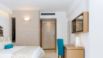 A bedroom with a bed, a desk, a mirror, and a door.