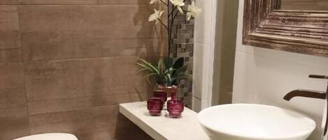 A bathroom with a toilet, sink, and decorative plants.