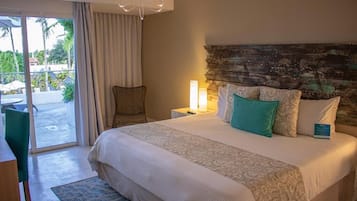 A hotel room with a large bed, a chair, a nightstand with a lamp, and a view of the outdoors through a sliding door.