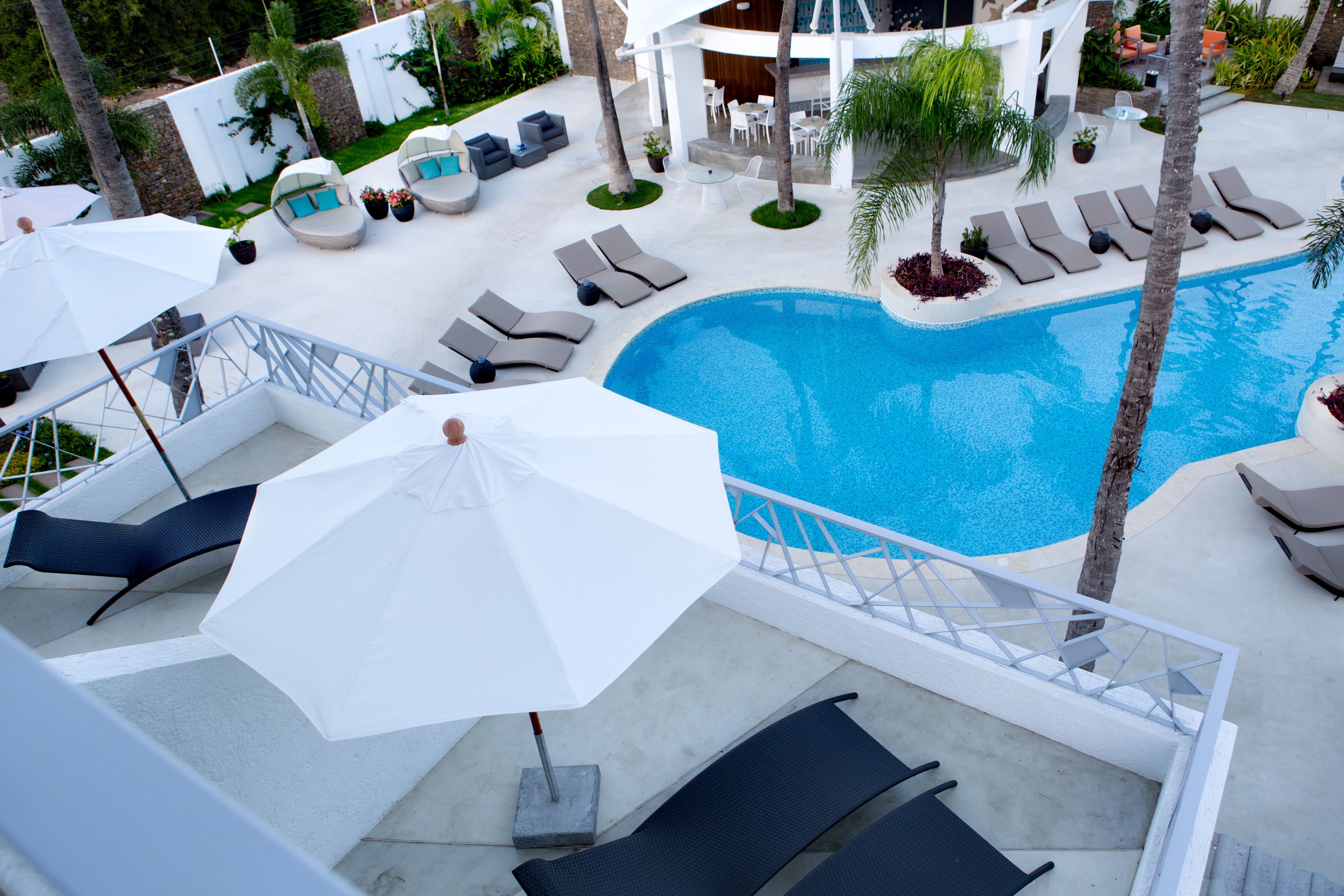 A poolside area with lounge chairs, umbrellas, and a swimming pool.